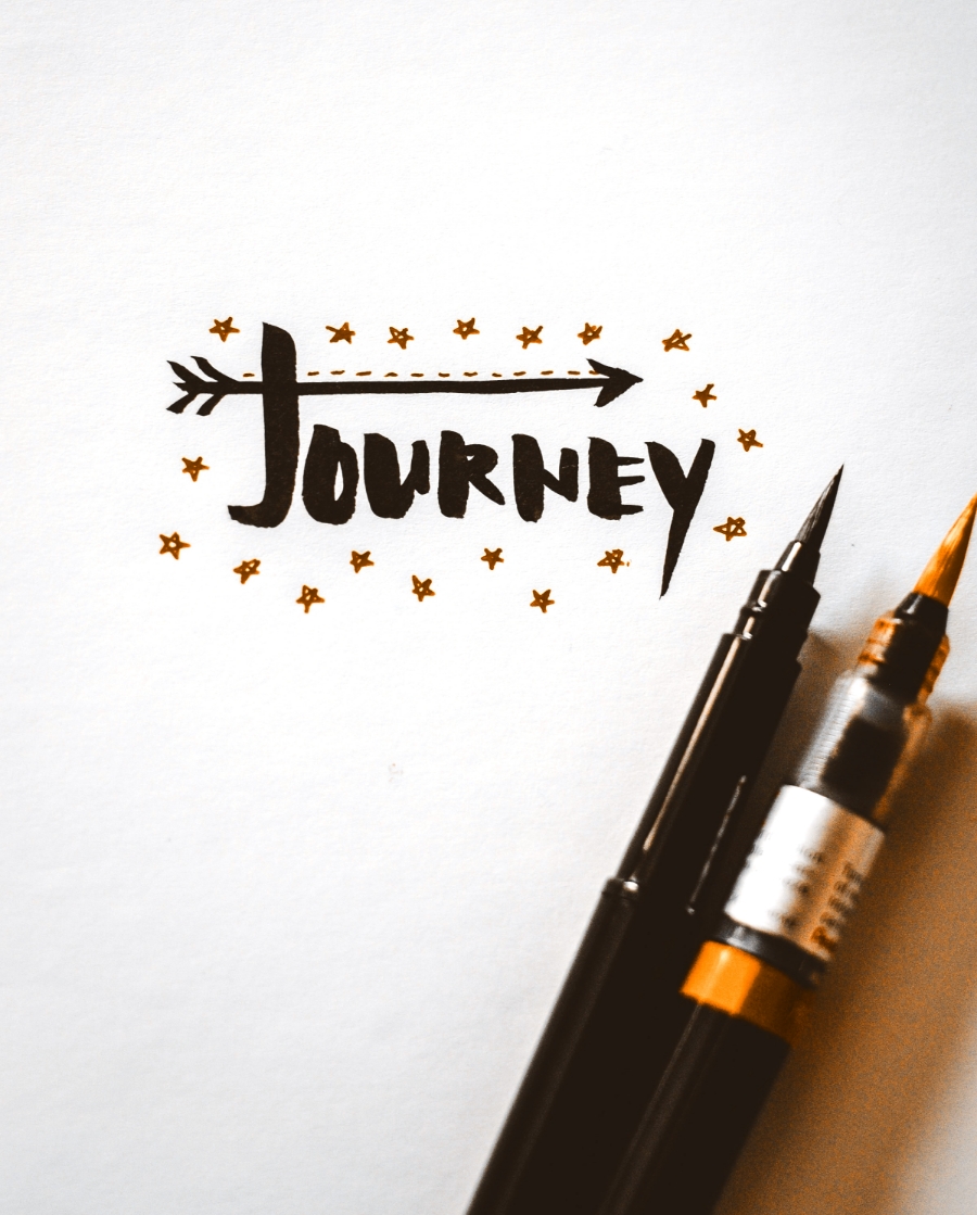 Die Reise einer Marke beginnt mit dem Branding. Auf dem Bild liegen Stifte und es steht das Wort Journey geschrieben.