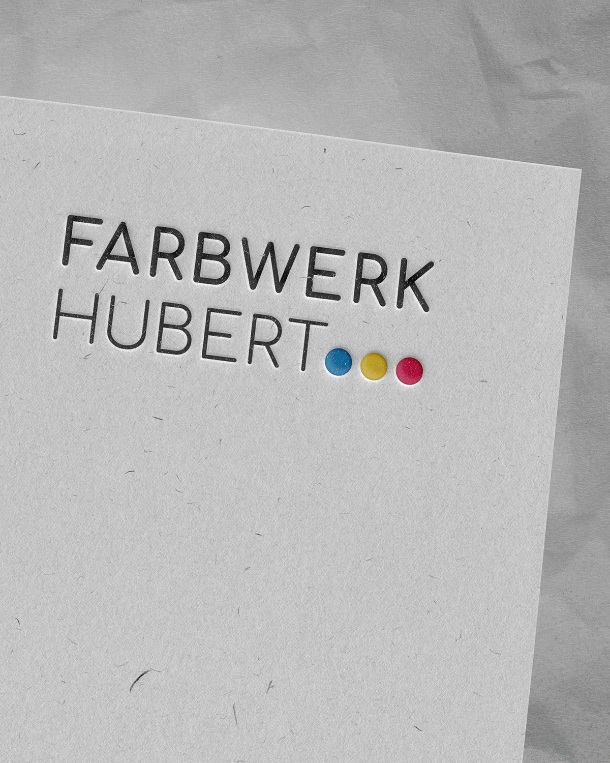 Das Bild zeigt das auf Papier geprägte Farbwerk Hubert Logo.