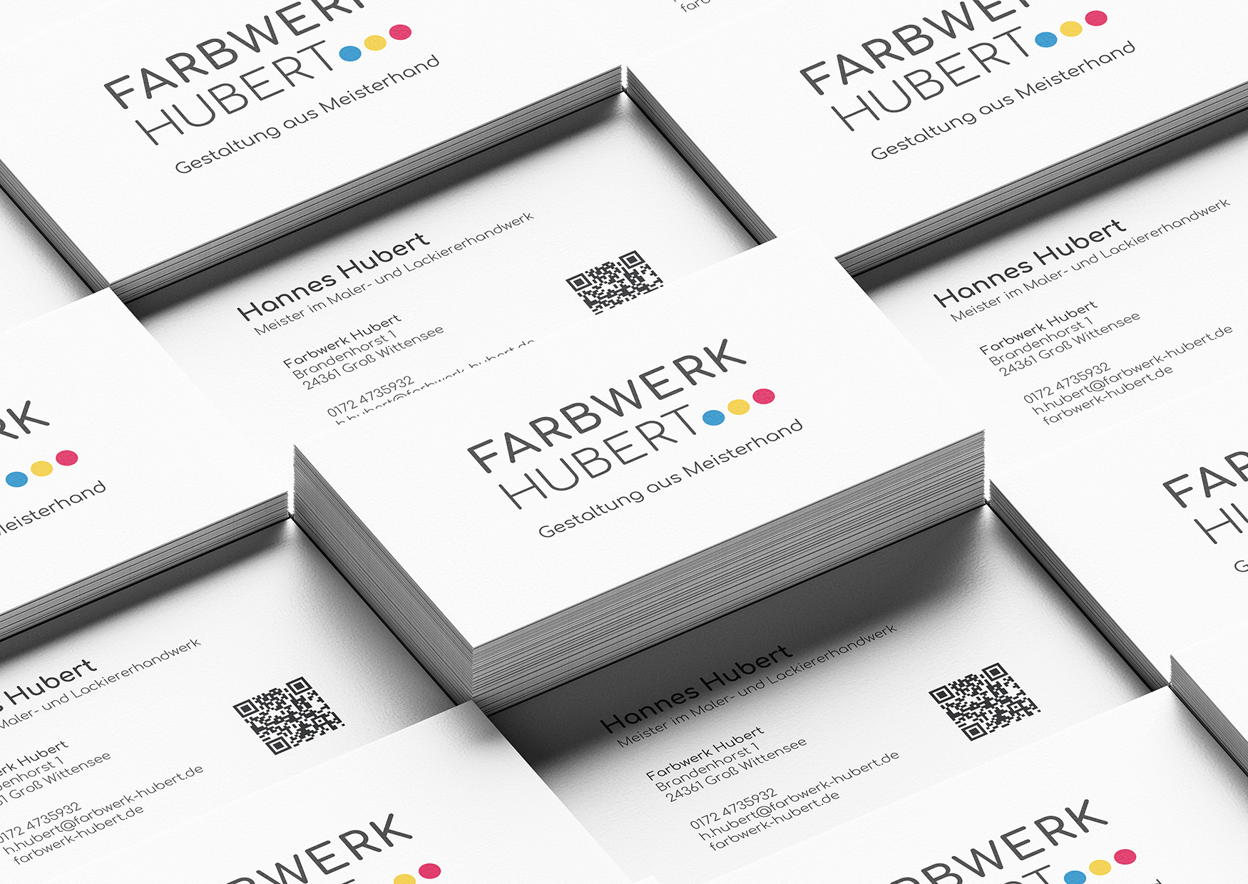 Auf dem Bild sind mehrere Stapel mit Visitenkarten von Farbwerk Hubert zu sehen.