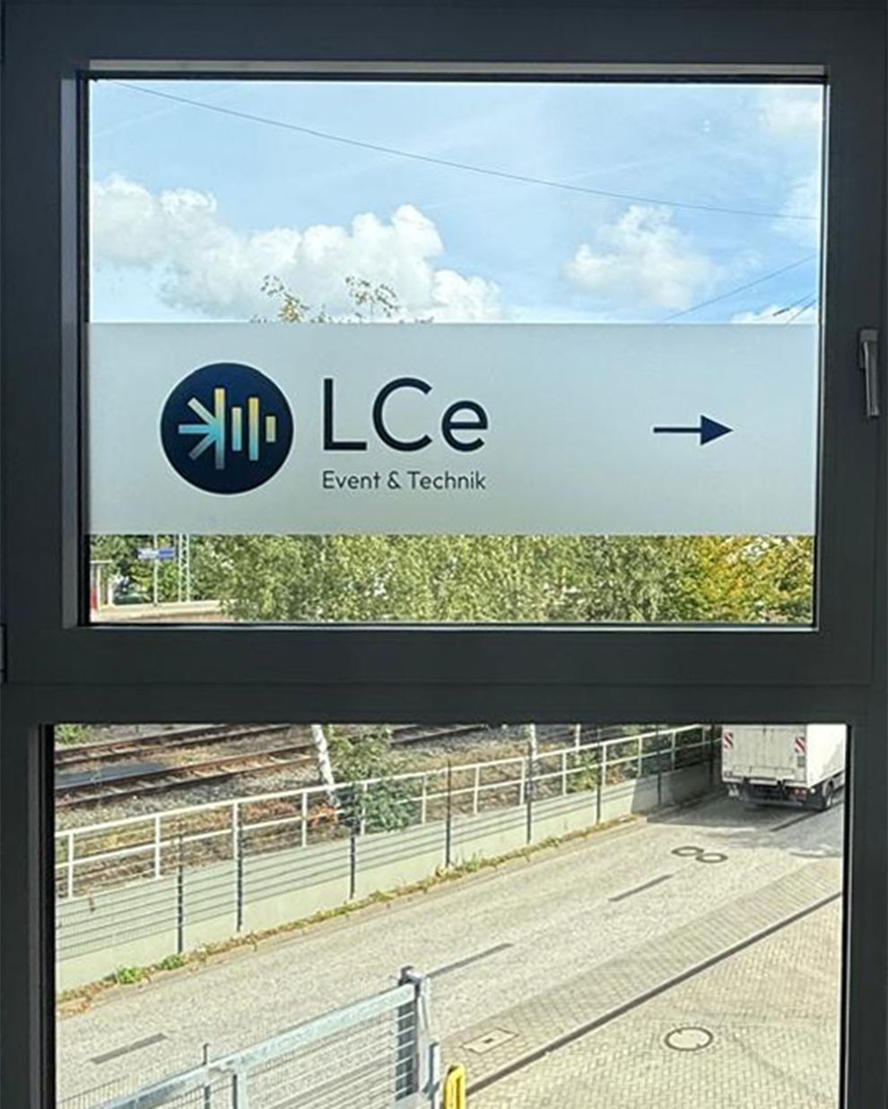 Eine Fensterscheibe ist mit Milchglasfolie beklebt, auf der das Logo zu sehen ist.